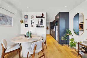 A modern kitchen with a round dining table, chairs, and various kitchen appliances. - Stylish Inner City Apartment (Collingwood)