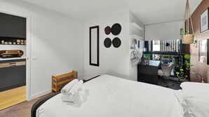 A modern hotel room with a bed, a desk, and a view of the city. - Stylish Inner City Apartment (Collingwood)