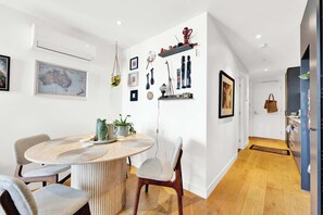 A modern dining area with a round table, chairs, and a hanging plant. - Stylish Inner City Apartment (Collingwood)