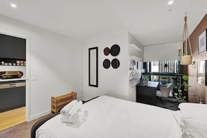 Une chambre d’hôtel moderne, équipée d’un lit, d’un bureau et offrant une vue sur la ville.