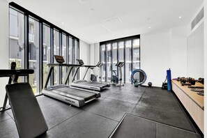 Une salle de sport moderne équipée de tapis de course, d’un rameur et de matériel d’haltérophilie.