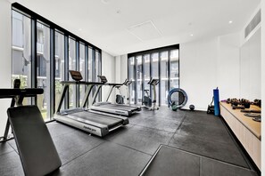 Une salle de sport moderne équipée de tapis de course, d’un vélo d’appartement et de matériel de musculation.
