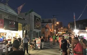 A crowded street scene at night with various shops and signs.