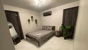Un dormitorio con cama, aire acondicionado, espejo y una planta en maceta.