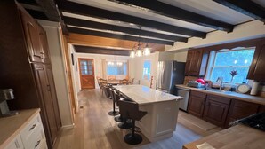 A spacious kitchen with a central island, wooden cabinets, and a large window providing natural light. - On Wyman Pond. Home on sprawling property with a pond, hiking & wildlife. (Sidney Center)