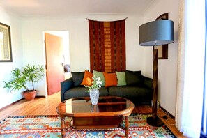 Een woonkamer met een bank, een salontafel, een lamp en een plant in pot.