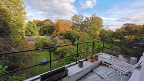 Ein Balkon mit Blick auf einen Garten und Häuser.