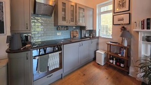 Eine moderne Küche mit grauen Schränken, einem eingebauten Backofen und einem Fenster, das für natürliches Licht sorgt.