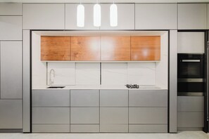 Een moderne keuken met een ingebouwde oven, een spoelbak en een houten bovenkast.