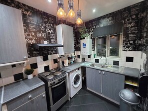 Une cuisine moderne avec un crédence à carreaux noirs et blancs, des appareils électroménagers en acier inoxydable et une fenêtre donnant sur la ville.