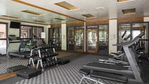 Een fitnessruimte met loopbanden, gewichten en trainingsapparatuur.