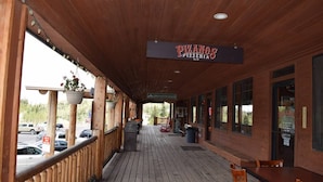 Een houten terras met een bord voor 'PIZANOS PIZZERIA' en een uitzicht op geparkeerde auto's.