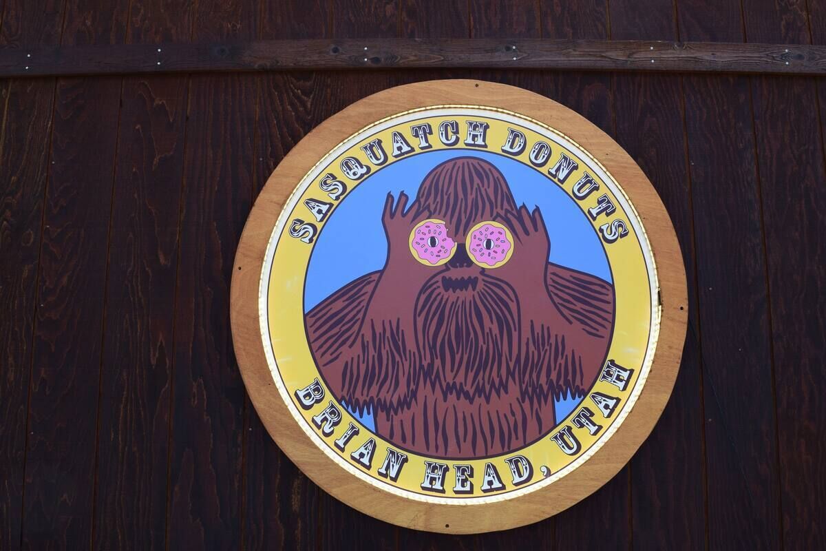 A circular sign with a bear illustration and text reading "Sasquatch Donuts Brian Head, Utah".