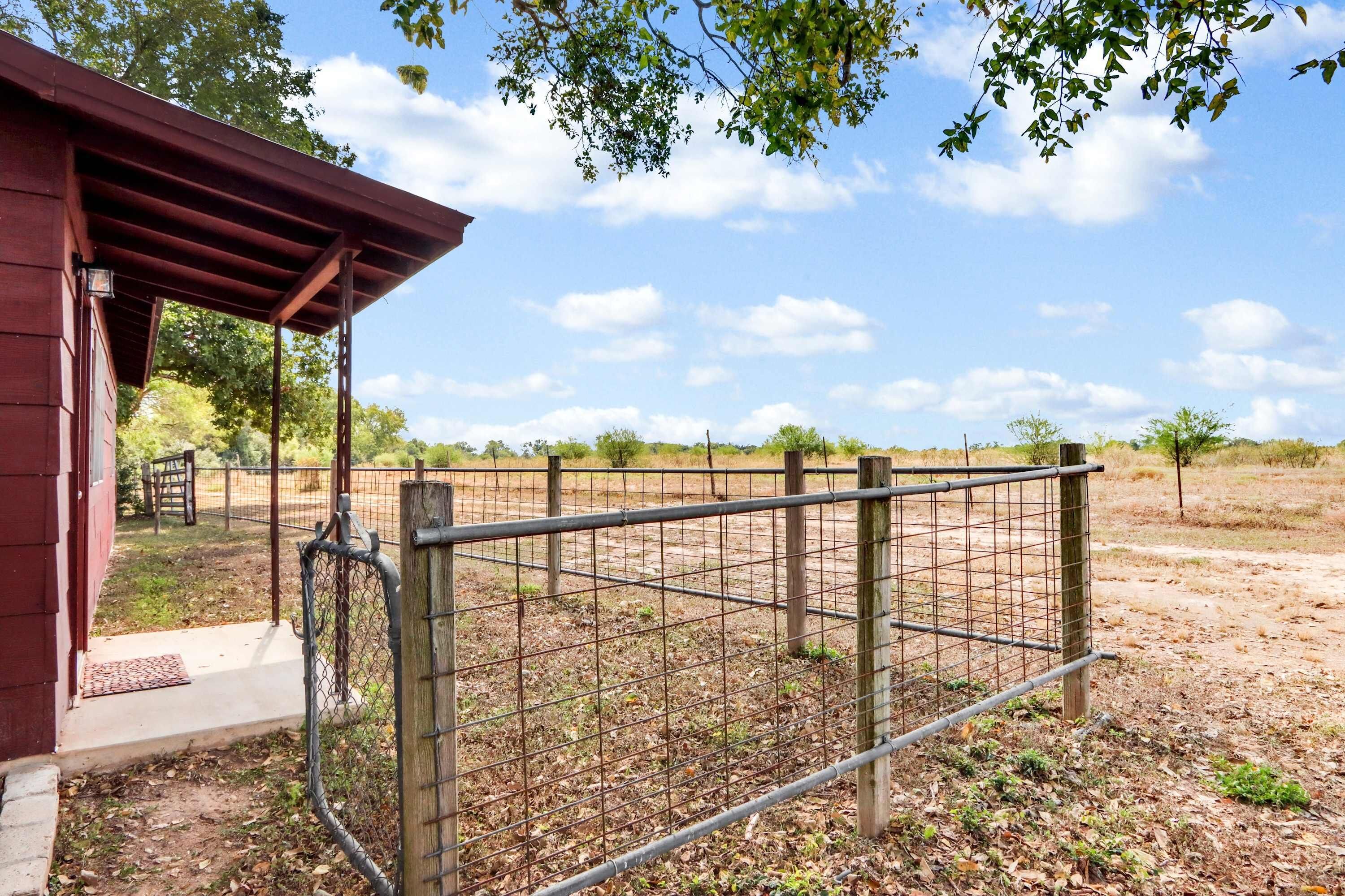 A fenced area with a wooden structure, possibly a barn or shed, and a clear sky.