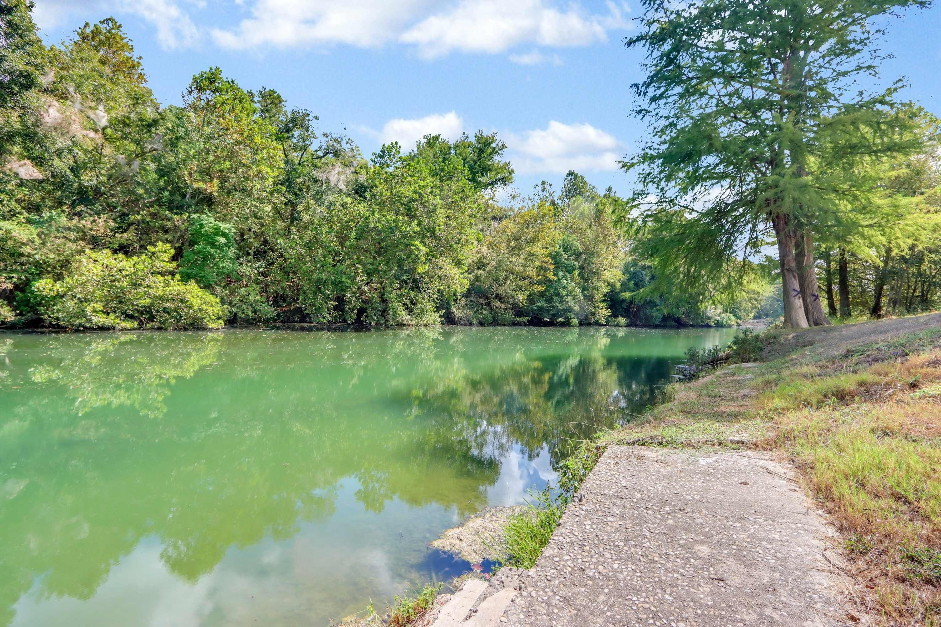 A calm river with dense greenery and trees on both sides.