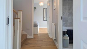 Ein Flur mit Holzboden, weißen Wänden und einer Treppe mit Holzwandungen.