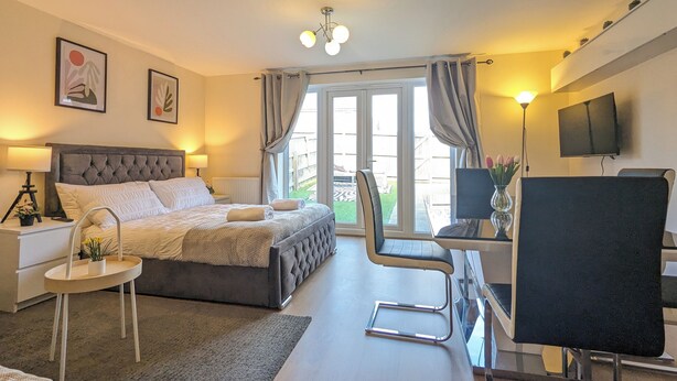 A modern bedroom with a large bed, a desk, a chair, and a TV. - This is a large three-story house, located near the city centre. A short 4-minute drive (1 mile) will take you to the city centre, Albert Dock, ACC. Convenient public transportation is available with a 10-minute bus ride from the city. centre. (Merseyside)