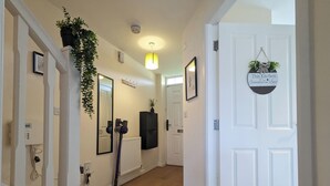 A hallway with a white door, a hanging plant, a framed picture, and a radiator. - This is a large three-story house, located near the city centre. A short 4-minute drive (1 mile) will take you to the city centre, Albert Dock, ACC. Convenient public transportation is available with a 10-minute bus ride from the city. centre. (Merseyside)