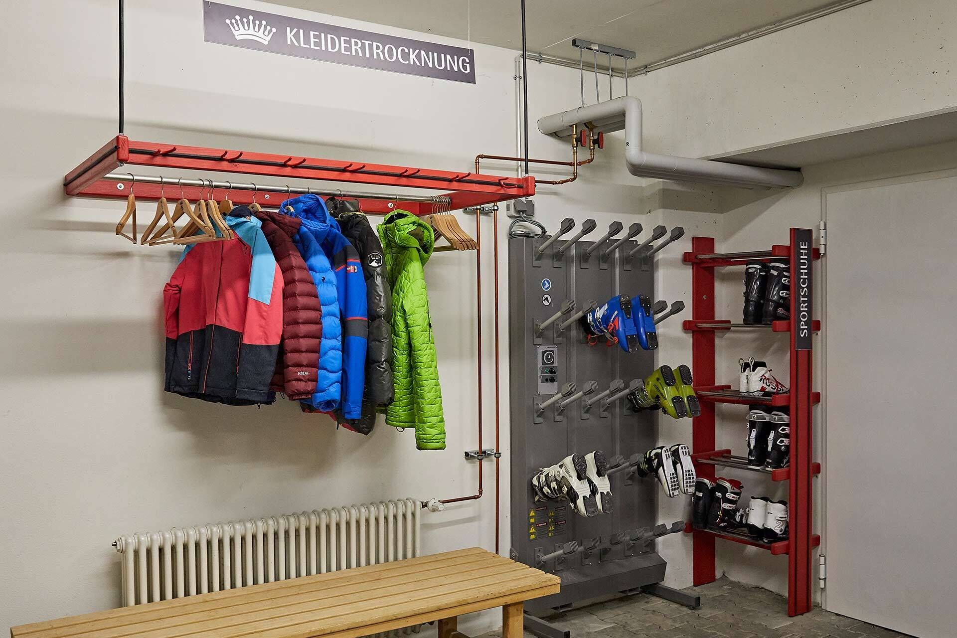 A locker room with multiple lockers, a coat rack with winter jackets, and a radiator.