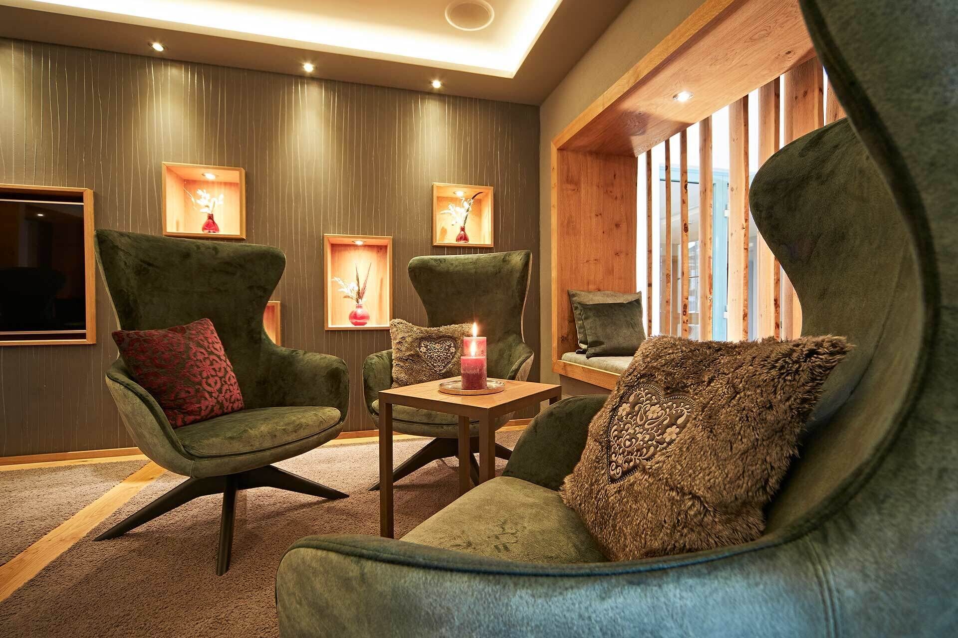 Una habitación acogedora con dos sillones verdes, una mesita de madera y una vela encendida.