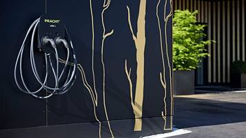 Un mur noir orné de motifs d’arbres dorés et une station de recharge « PRACT » LPH.