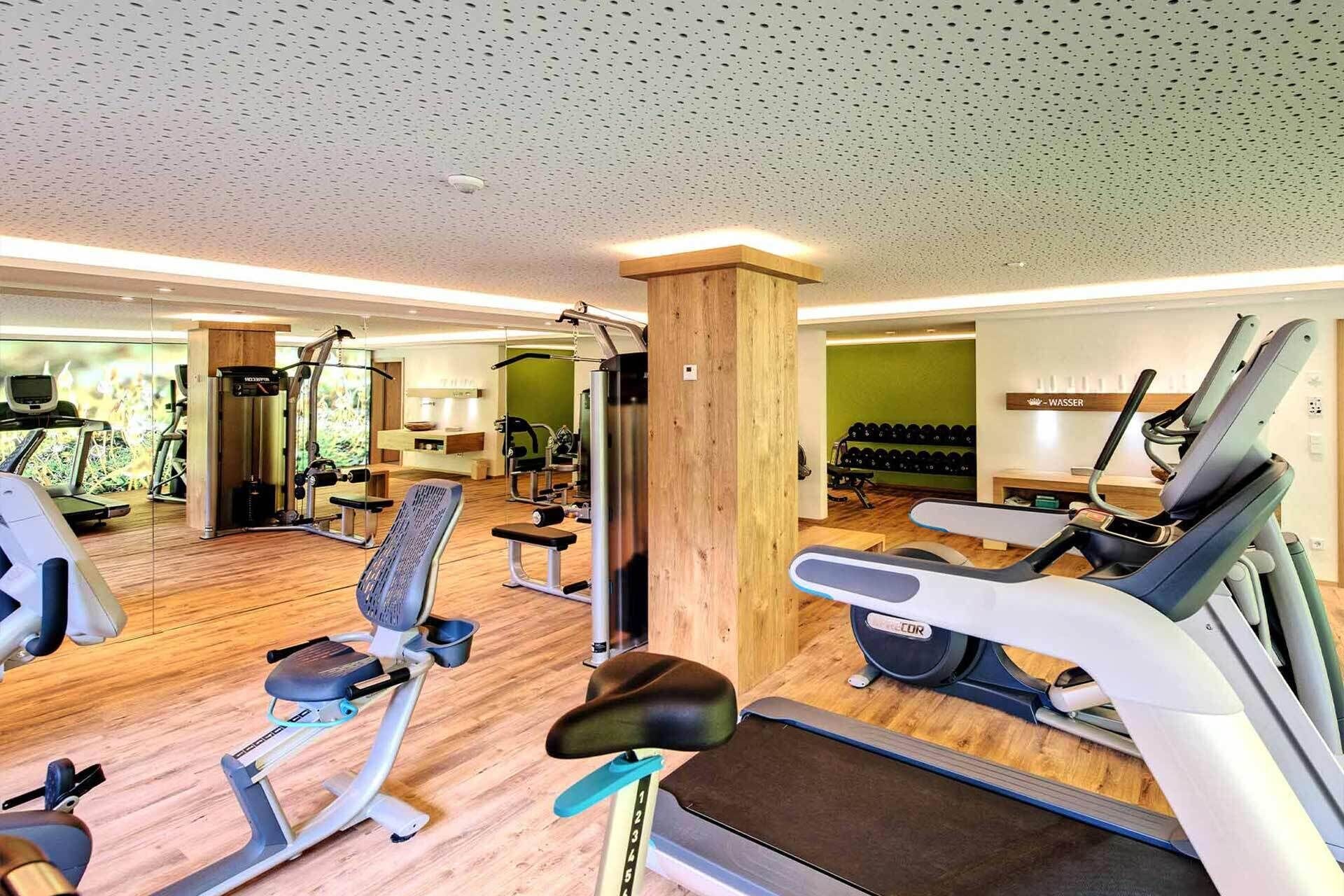 A gym with cardio machines, weightlifting equipment, and a mirror.
