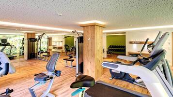 A gym with cardio machines, weightlifting equipment, and a mirror.