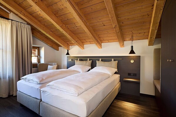 A bedroom with two beds, wooden ceiling beams, a window, and a door. - Hotel Restaurant Die Krone (Immenstadt im Allgaeu)