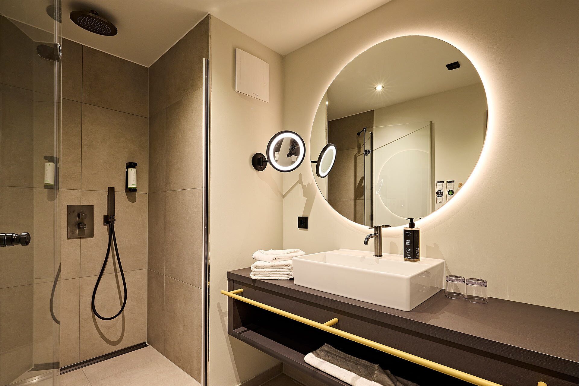 Ein modernes Badezimmer mit Dusche, Waschbecken inklusive Spiegel und einem Handtuchhalter.