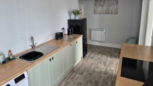 Une cuisine compacte équipée d’un évier, d’un grille-pain, d’une bouilloire, d’un réfrigérateur et d’un radiateur.