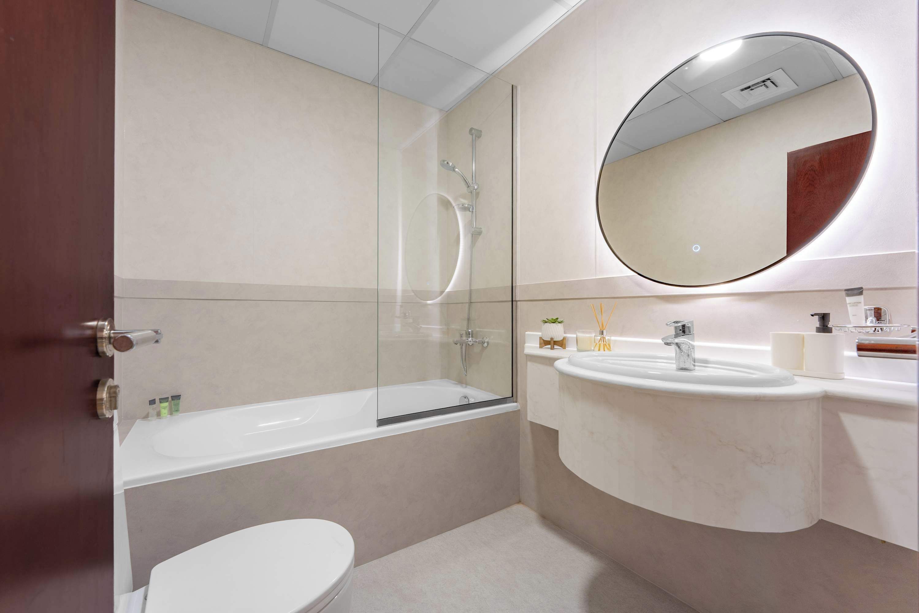Un baño moderno con ducha de vidrio, inodoro blanco y tocador con espejo.