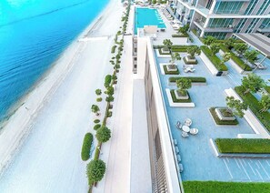 An aerial view of a resort with a pool, beach access, and landscaped areas. - StayShort - Luxury Living at Emaar Beachfront with Stunning Water Views! (Emaar Beachfront)