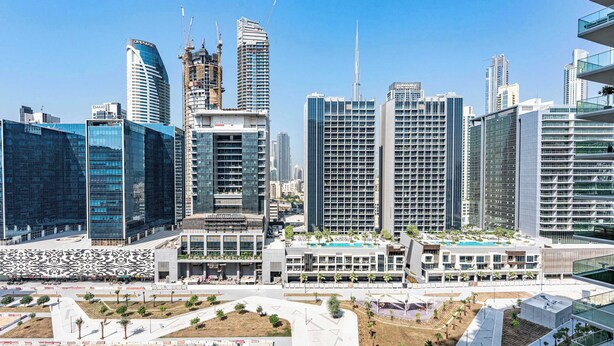 Un paysage urbain moderne, caractérisé par des immeubles de grande hauteur, dont un gratte-ciel à la forme incurvée remarquable, ainsi que plusieurs bâtiments en construction.