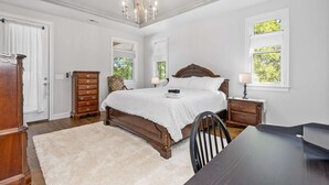 A bedroom with a large bed, a wooden dresser, a chair, and a desk. - Walkable Hillsboro Home - Near 12 South & Vandy (Nashville)