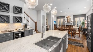 A modern kitchen with a large island, stainless steel appliances, and pendant lighting. - Walkable Hillsboro Home - Near 12 South & Vandy (Nashville)