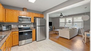 A modern kitchen with wooden cabinets, stainless steel appliances, and a dining area with a sofa and table. - Home near DTWS, UNCAS, WFU, Hospitals, food/bev! (Winston-Salem)