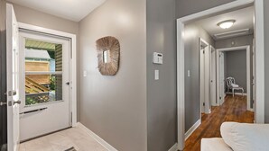 A hallway with a white door, a wall-mounted mirror, and a thermostat. - Home near DTWS, UNCAS, WFU, Hospitals, food/bev! (Winston-Salem)