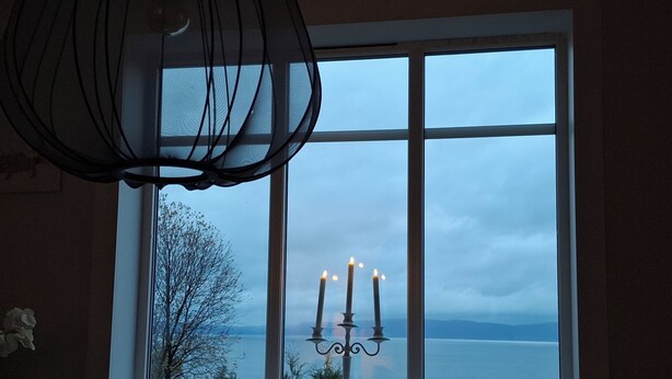 A room with a large window, a chandelier, and a view of a body of water.