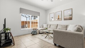 A modern living room with a sofa, coffee table, and a TV on a stand. - Family Resort Getaway w Pool Patio Near Disney (Kissimmee)