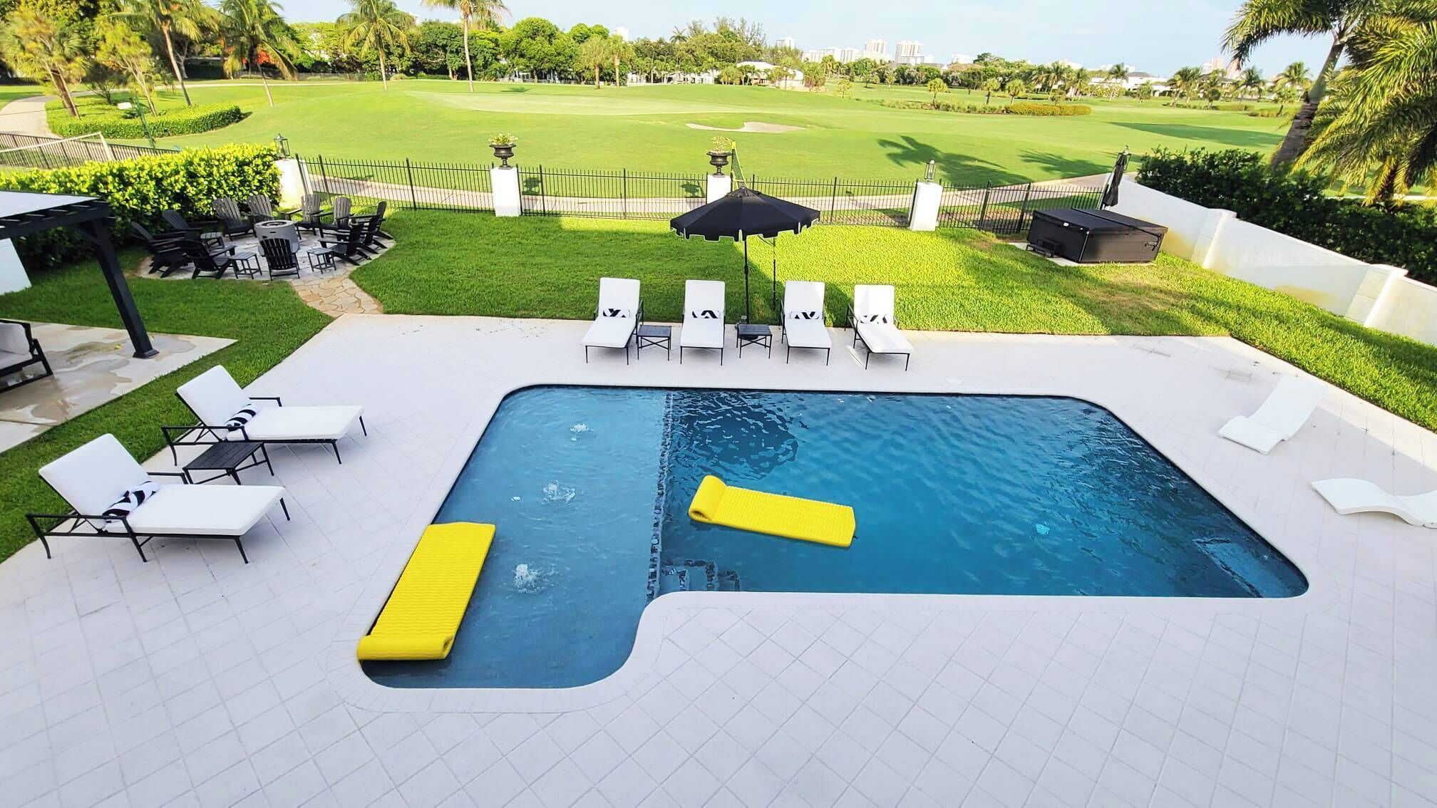 Une piscine avec des chaises longues et, au loin, un terrain de golf.