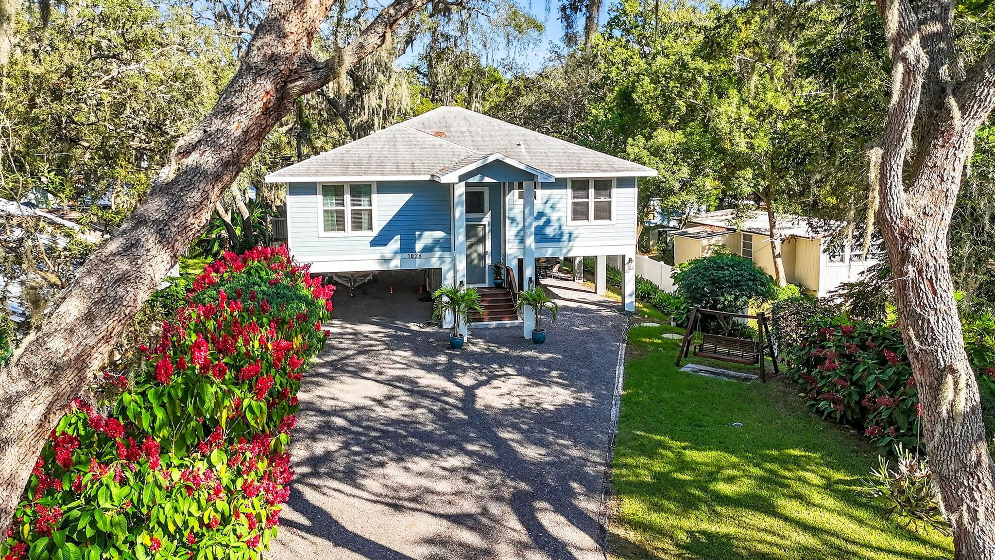 A two-story house with a front porch, surrounded by trees and a well-maintained garden.