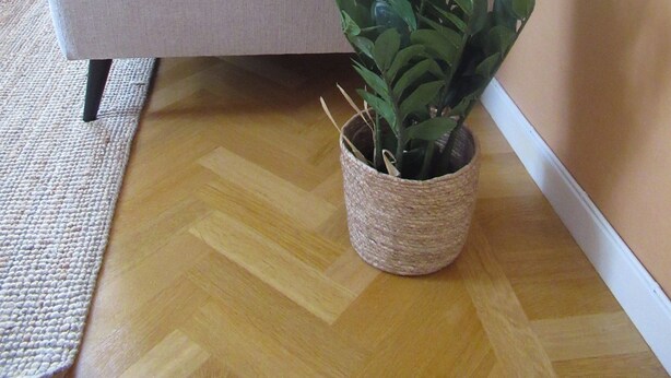 A living room with a grey sofa, a woven plant pot, and a wooden floor. - Porter House Tingshus (Hammarstrand)