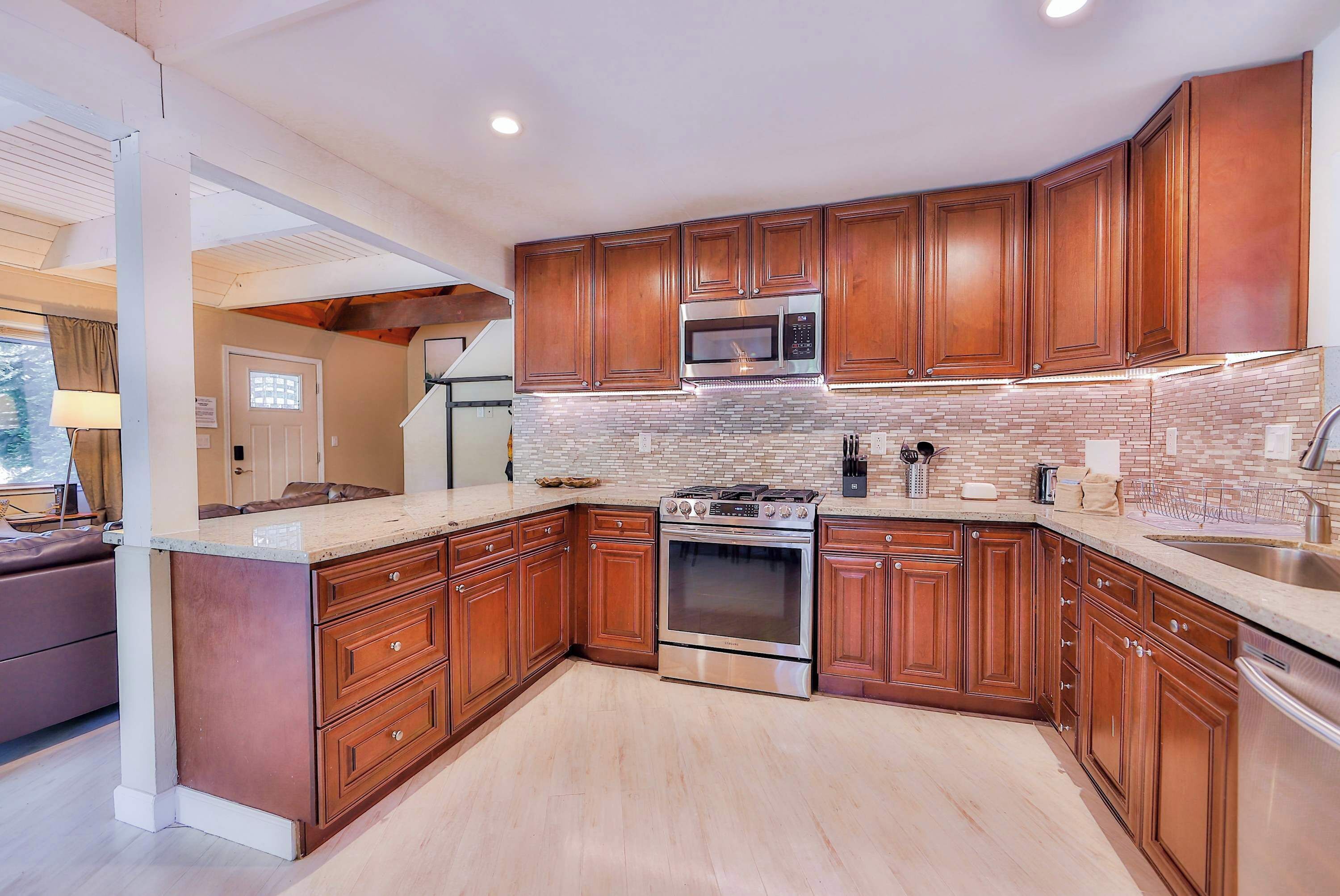 A modern kitchen with wooden cabinets, a stainless steel stove, and a microwave.