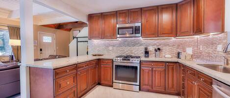 A modern kitchen with wooden cabinets, a stainless steel stove, and a microwave.