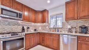 A modern kitchen with wooden cabinets, stainless steel appliances, and a tiled backsplash. - Iroquois Ridge Charming Home for 8 w/ Hot Tub Near Lake Tahoe & Skiing (South Lake Tahoe)