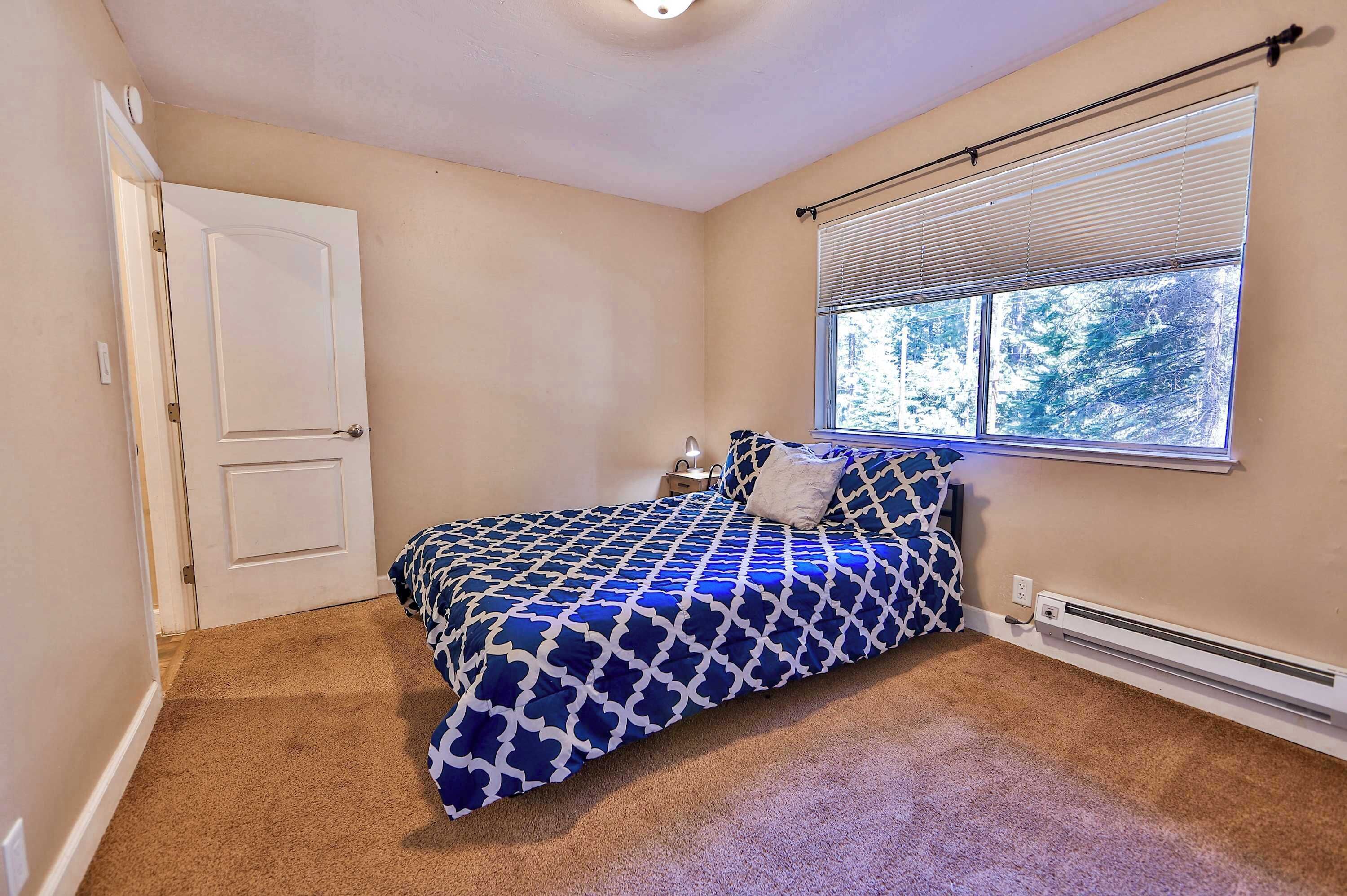Un dormitorio con cama, ventana con persianas, puerta y un calentador de pared.