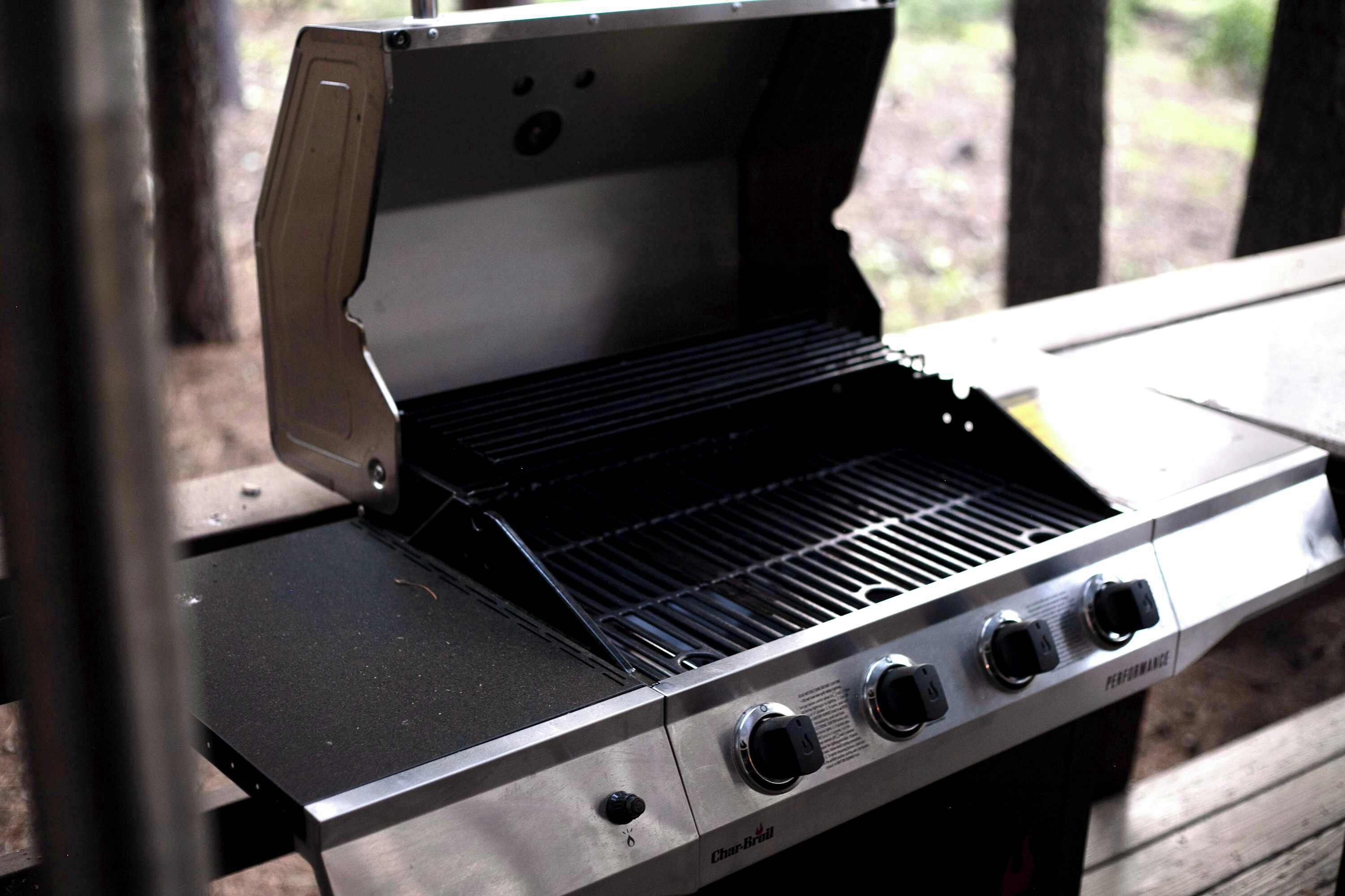 A Char-Broil gas grill with four burners and a side shelf, set on a wooden deck.