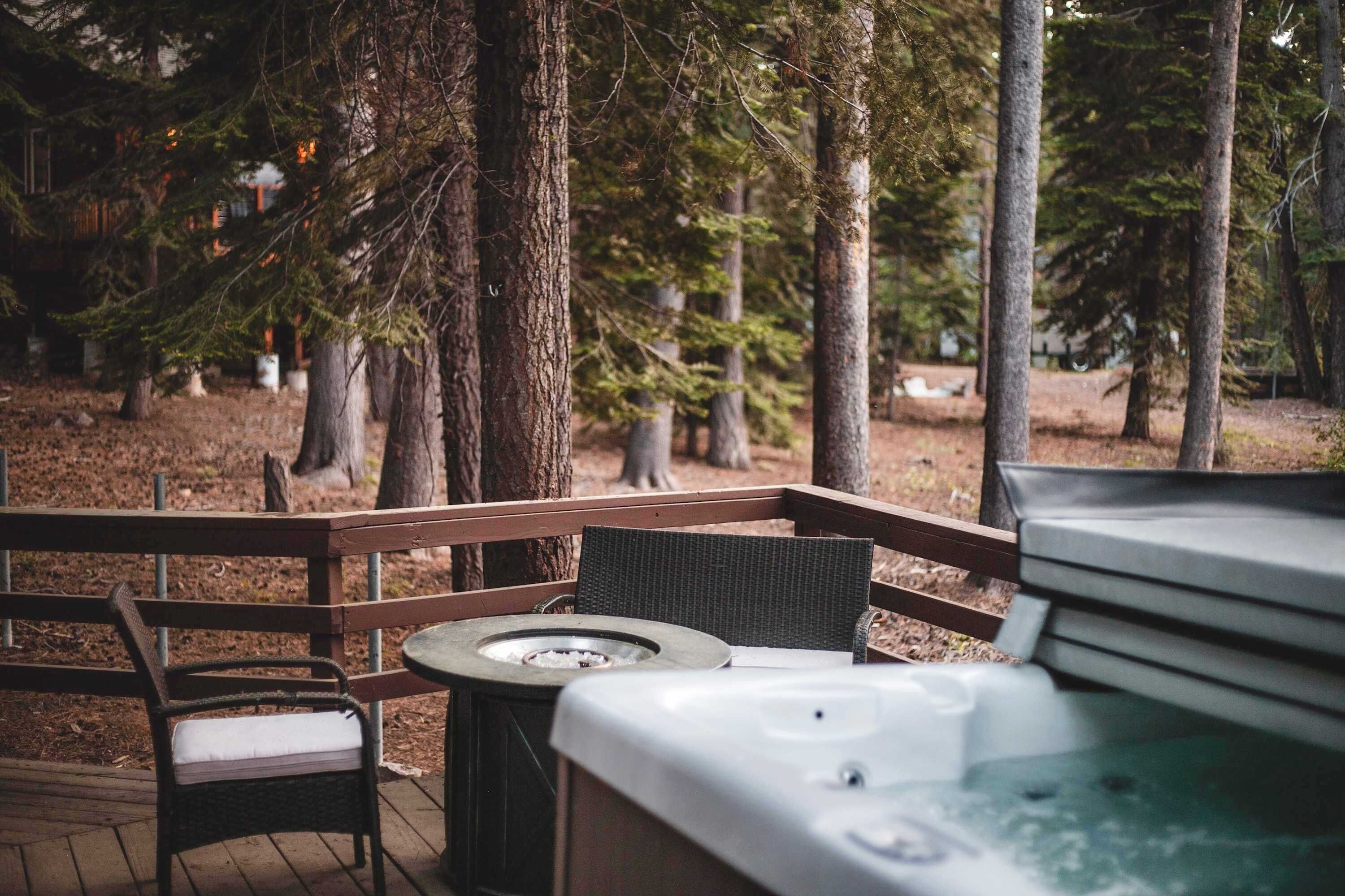 An outdoor seating area with a hot tub, wooden deck, and chairs.