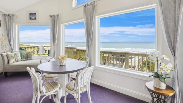 A room with a round table and chairs, a sofa, and a view of the ocean. - SS3 - Oceanfront 6 bedroom, 5 bath, dune top deck w/ hot tub, billiards table (Southern Shores)