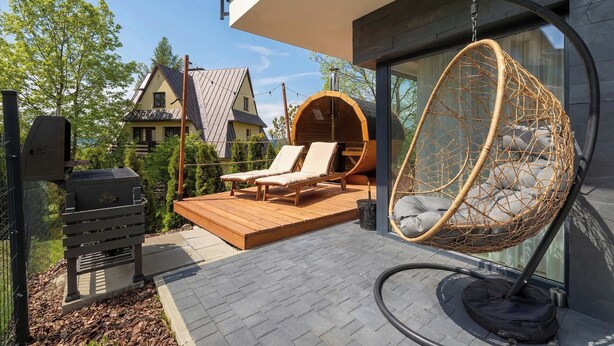 A modern outdoor deck with a grill, lounge chairs, and a hanging chair. - Spacious Apartment in Zakopane | Terrace with a View, Sauna, Parking (Zakopane)